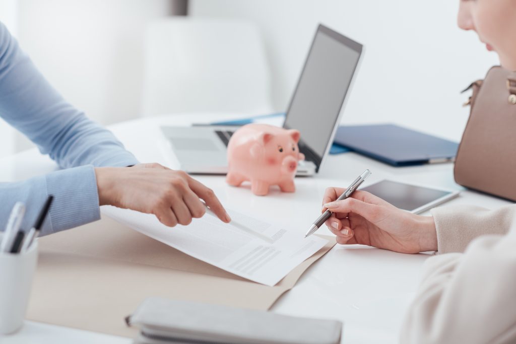 Financial advisor and woman meeting in the office, the customer is reading and signing a contract.